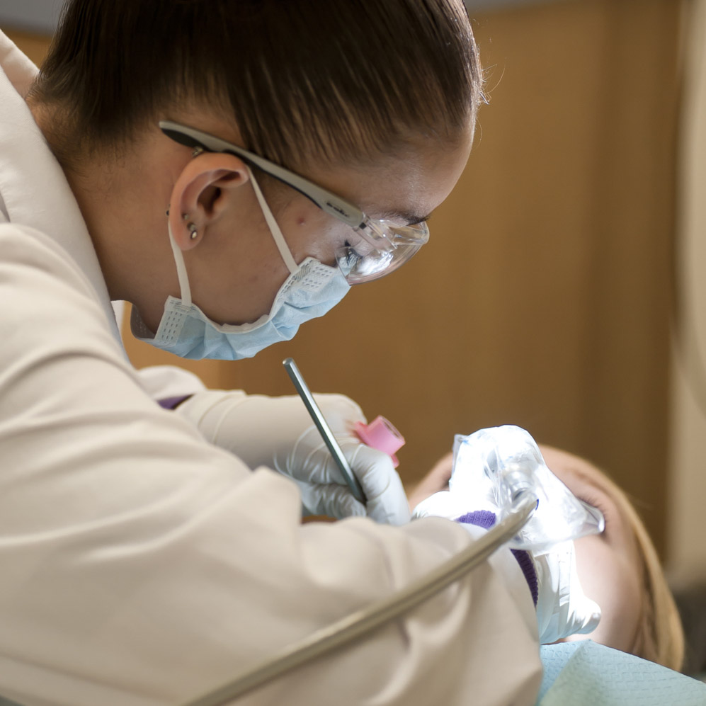 white female dental assisting student working on white female patient
