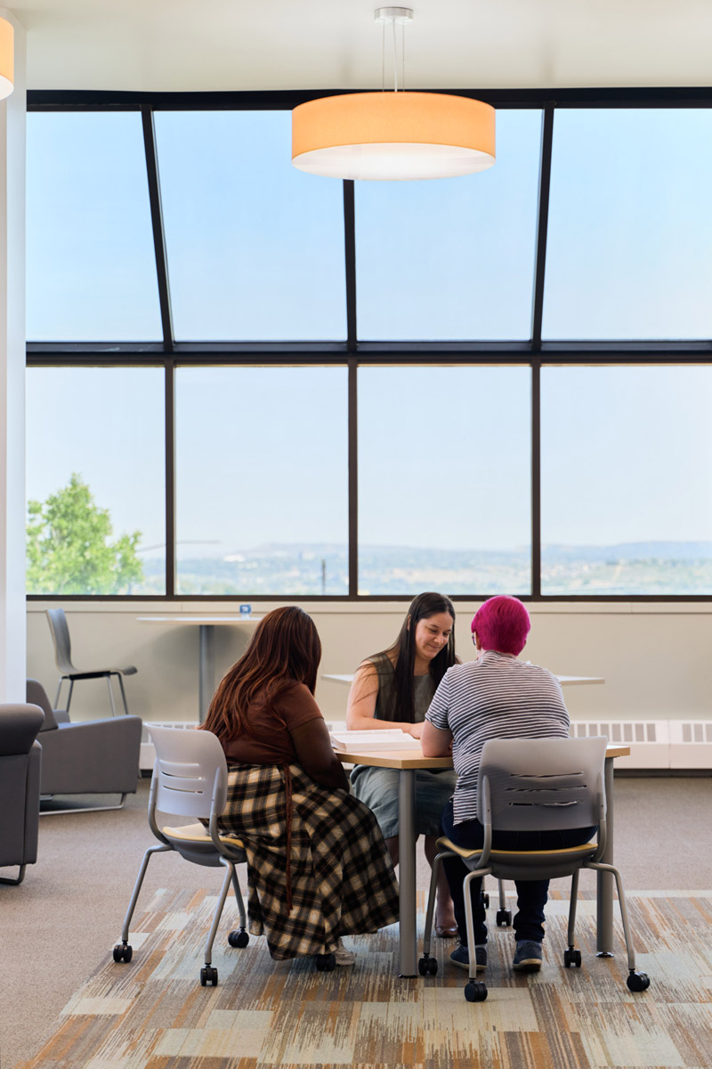 Employees at a table in the library reading books.