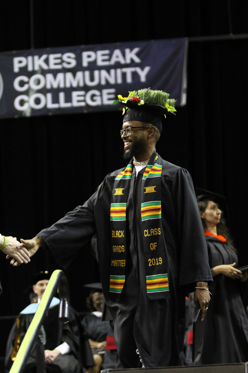 Student wearing sashes and shaking hands at commencement