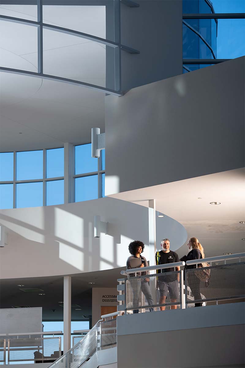 Students standing in the distance on the second floor of the atrium at the Rampart Range Campus.