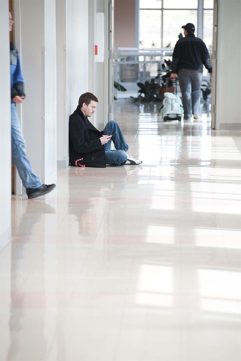 Student sitting on the floor in the hallway. 