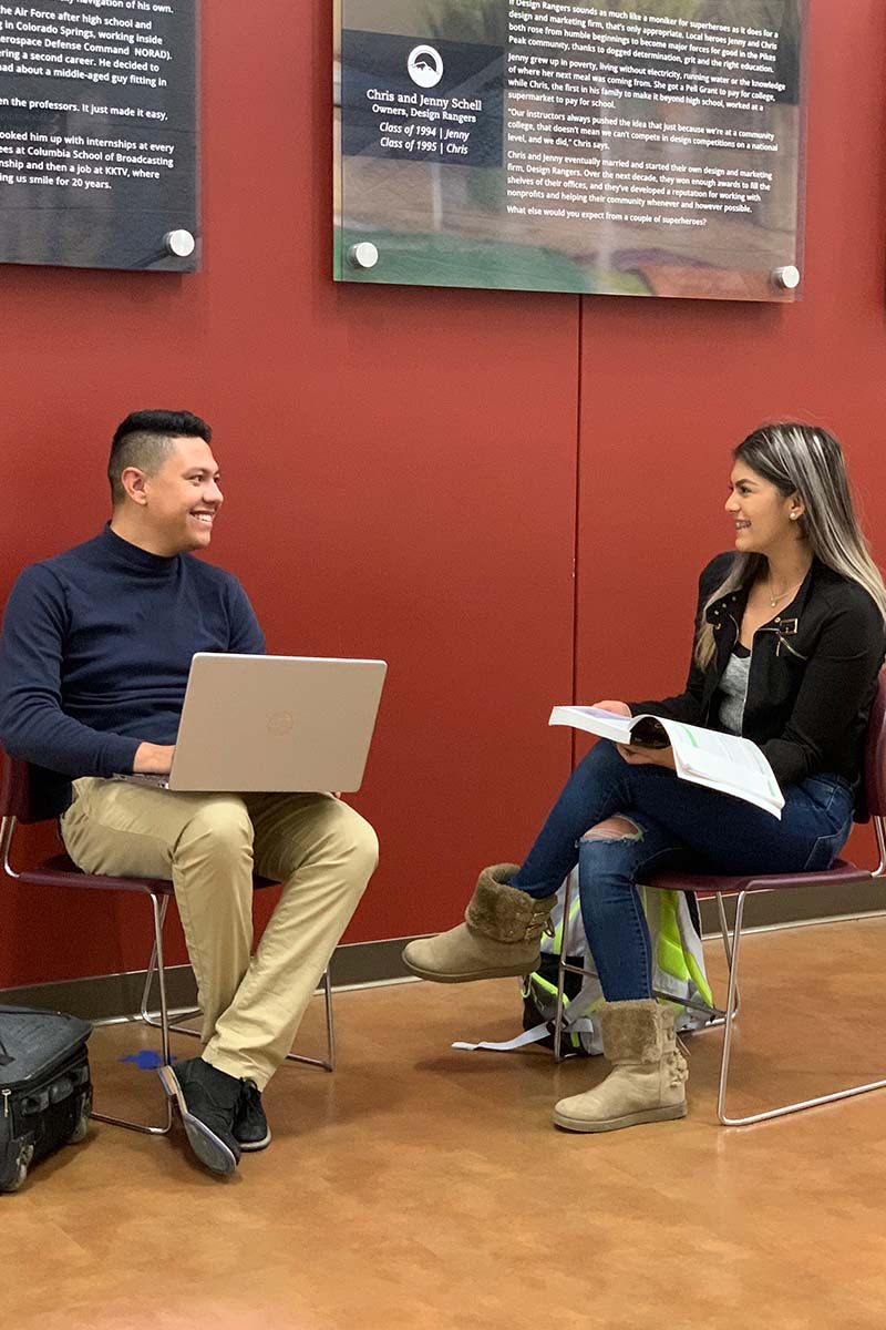 Students smiling as they sit next to each other. 