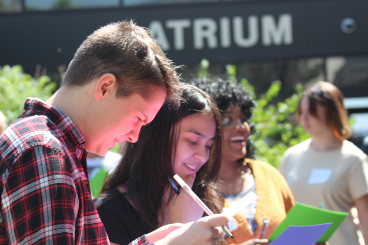 three students looking down on paper and smiling