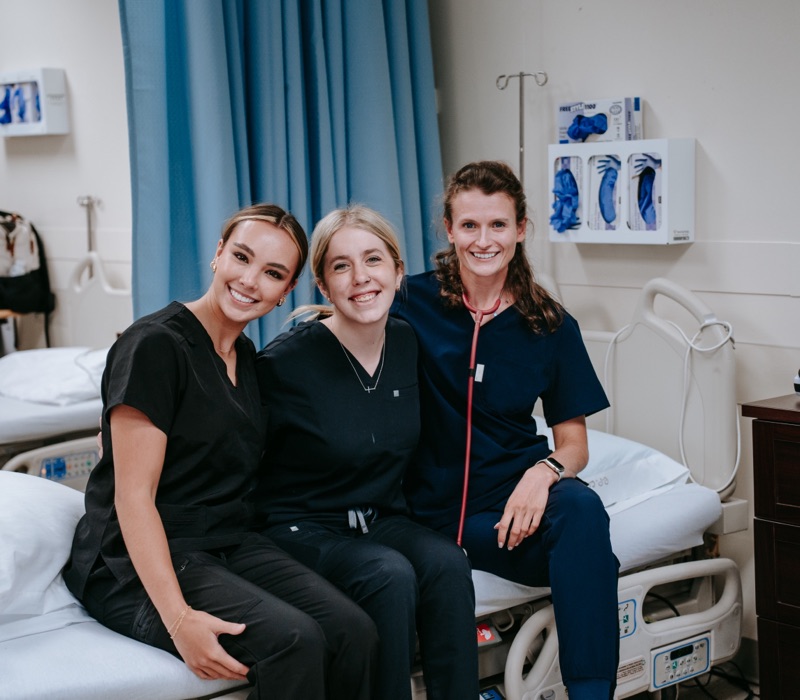 Three PPSC nursing students smiling together in a clinical lab
